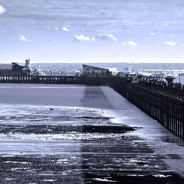 Southend-on-Sea Pier in Essex, UK, extending into the water with a view of the beach at low tide.